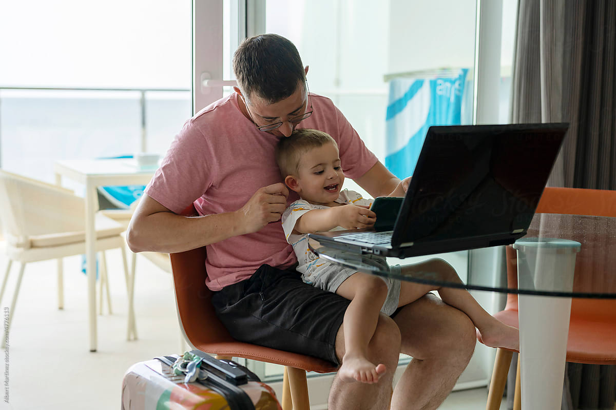 Man works on vacation while baby plays