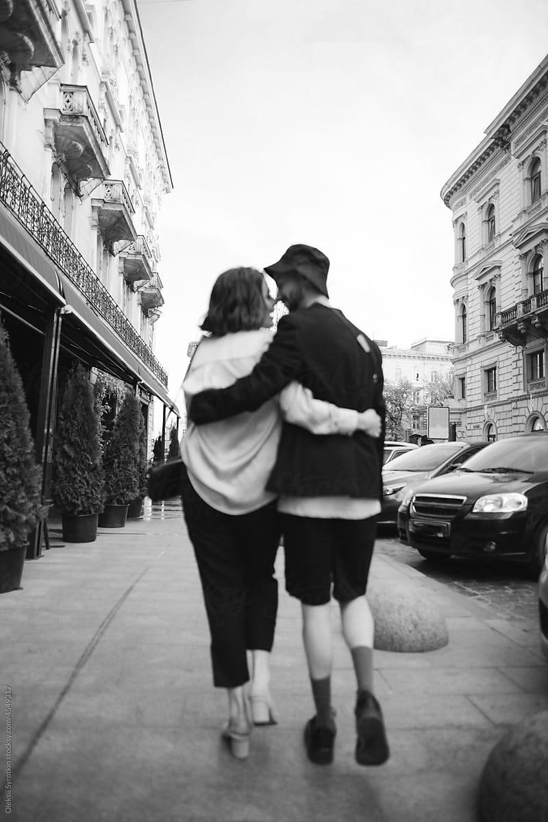 Man and woman embracing during walk in city and looking at each other