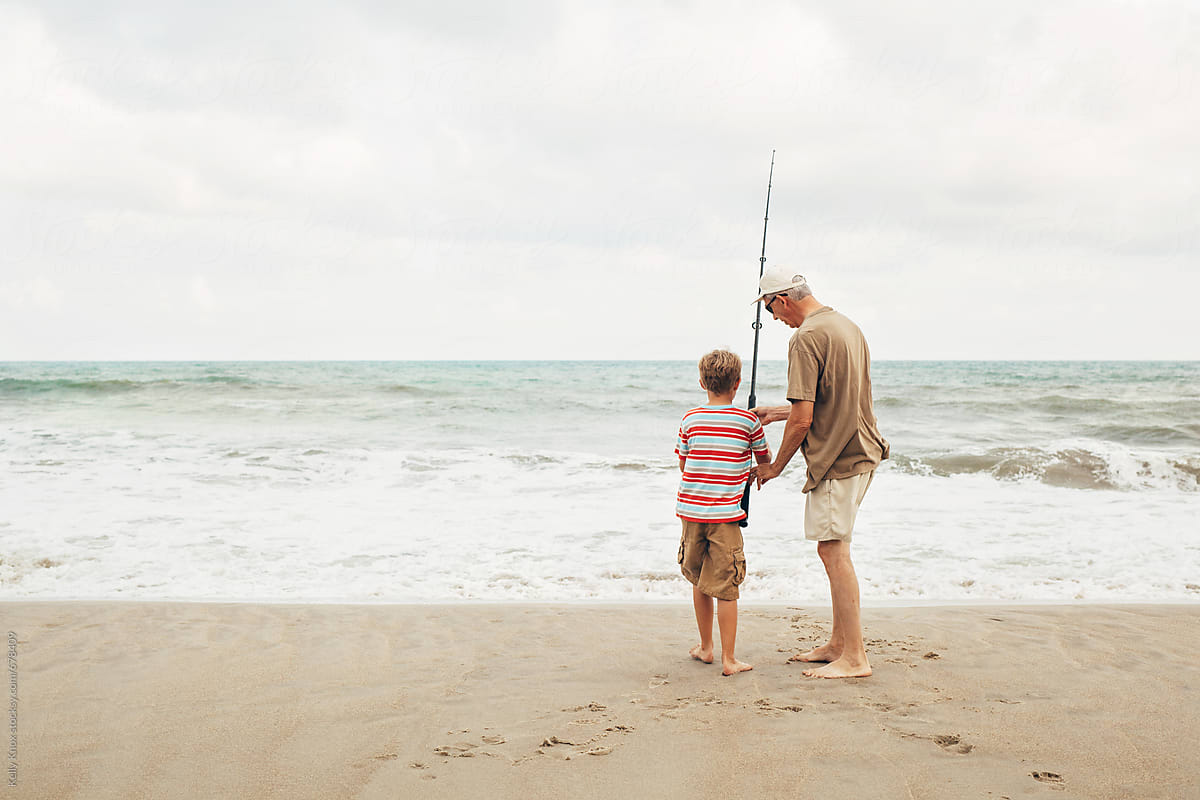 grandfather and child surf fishing on the beach
