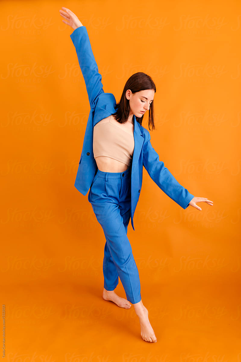 Focused woman practicing dance in room with orange wall
