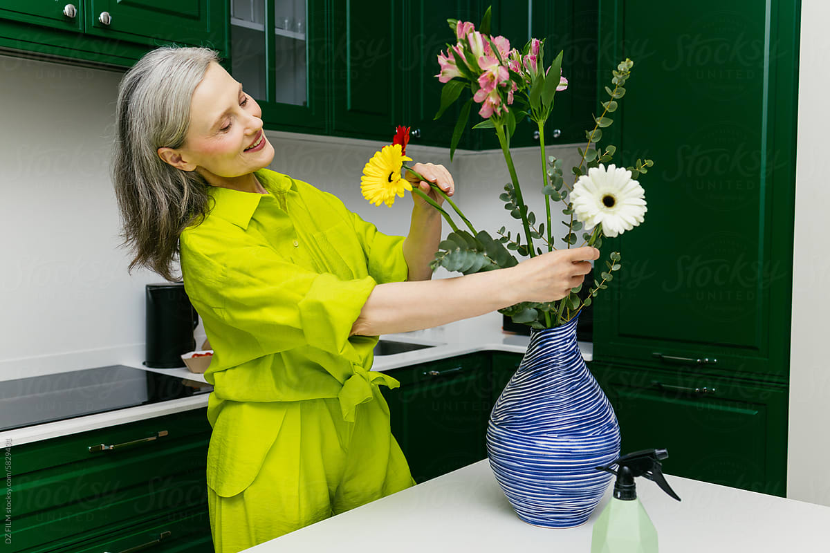 A woman makes a flower arrangement in the kitchen