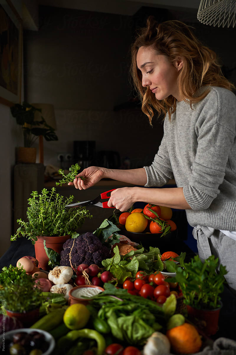 Woman preparing healthy vegetarian meal with vegetables and herbs