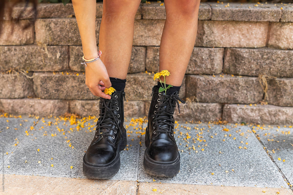 unrecognizable teenager putting flowers inside her boots