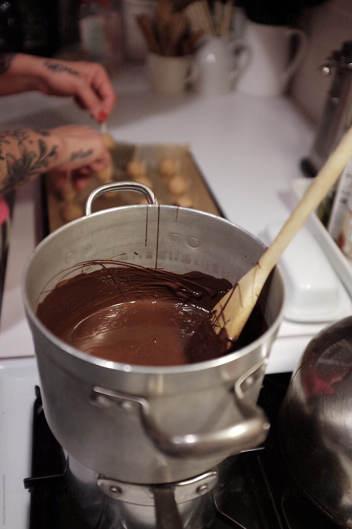 A woman with tattoos on her hands baking chocolate covered desserts in the kitchen