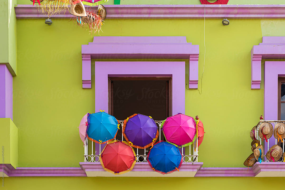 Colored umbrellas hanging from the window of a balcony