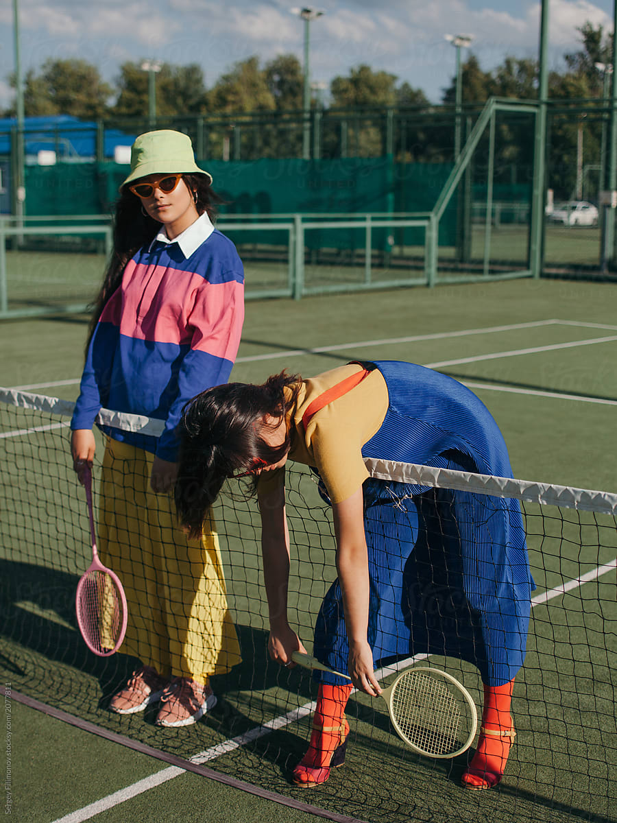 Trendy women standing at tennis net