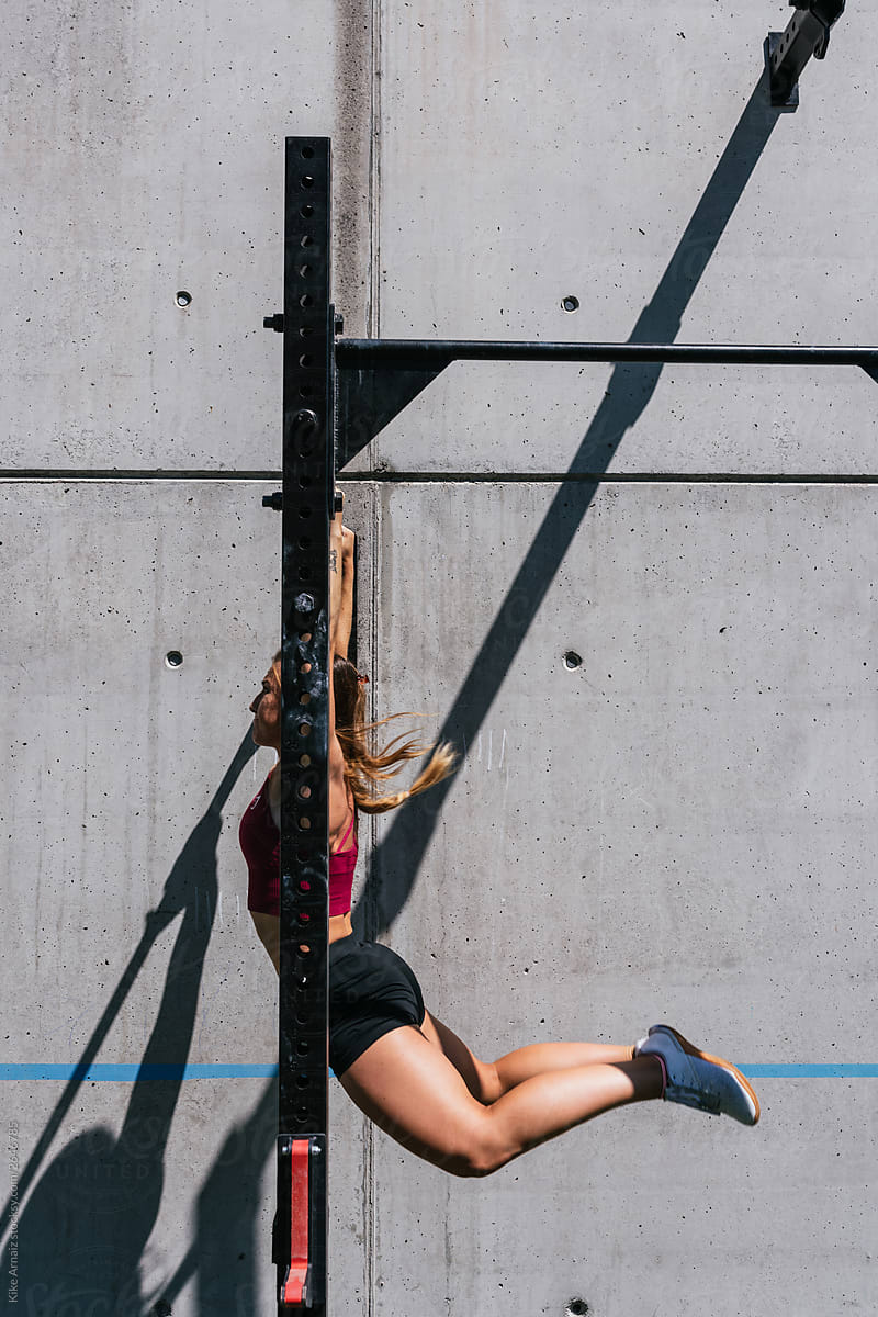 side view of woman doing pull up exercise on horizontal bar