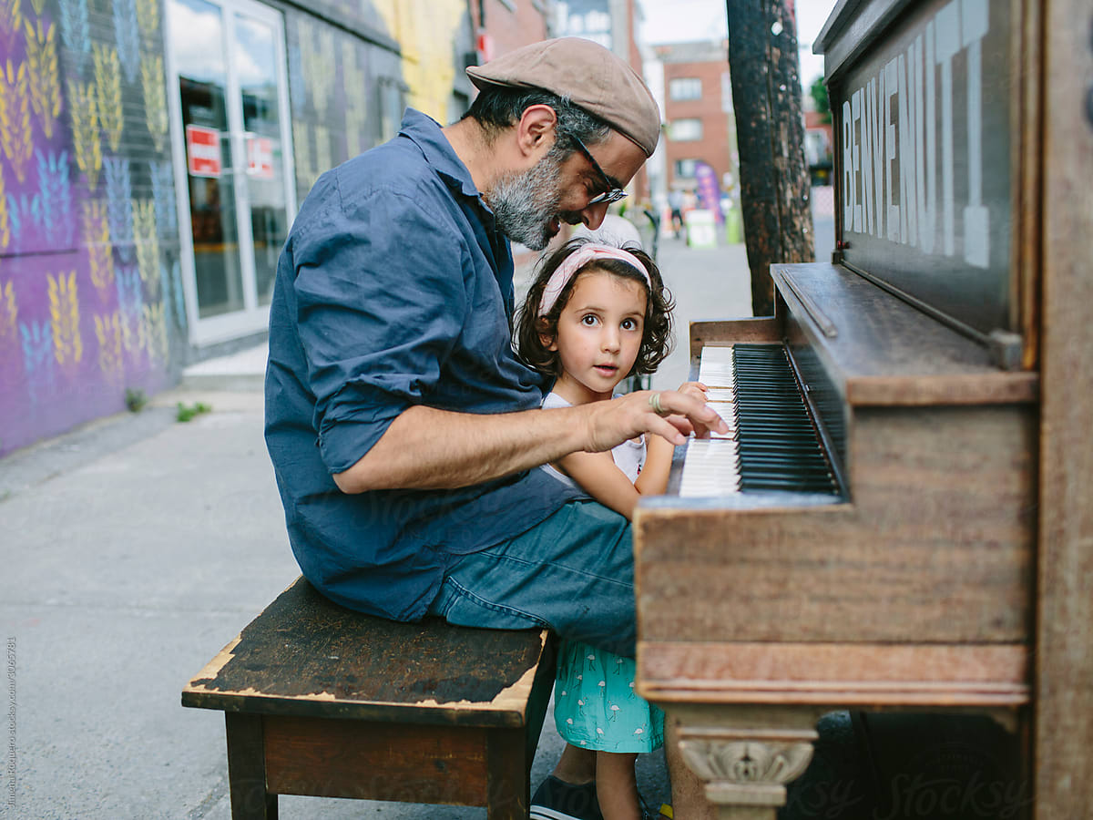 Father and daughter playing piano in the street