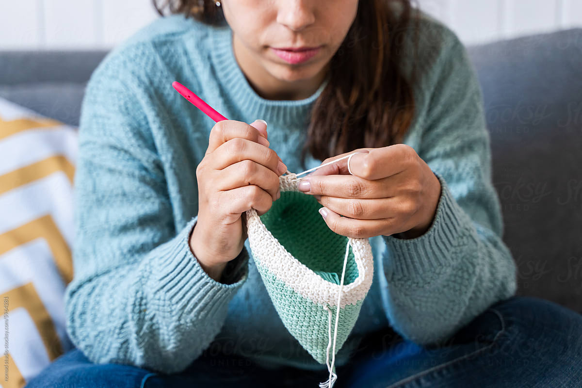 Young woman focused on crocheting a beanie at home