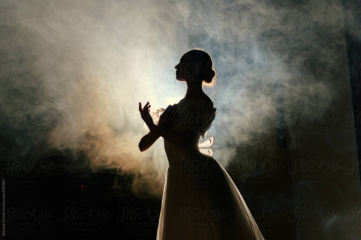 Ballerina in dress posing in darkness