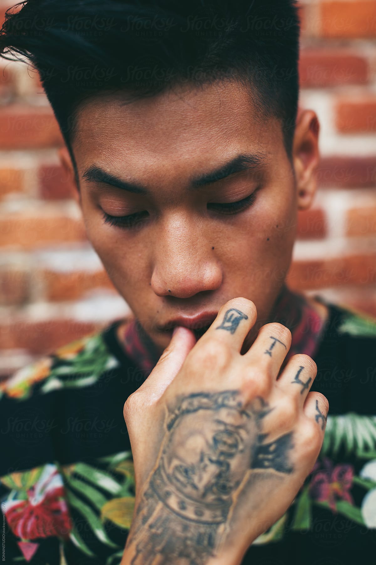 Closeup Portrait Of A Young Asian Man With Tattooed Hand Standing Outside." by Stocksy Contributor "BONNINSTUDIO " - Stocksy