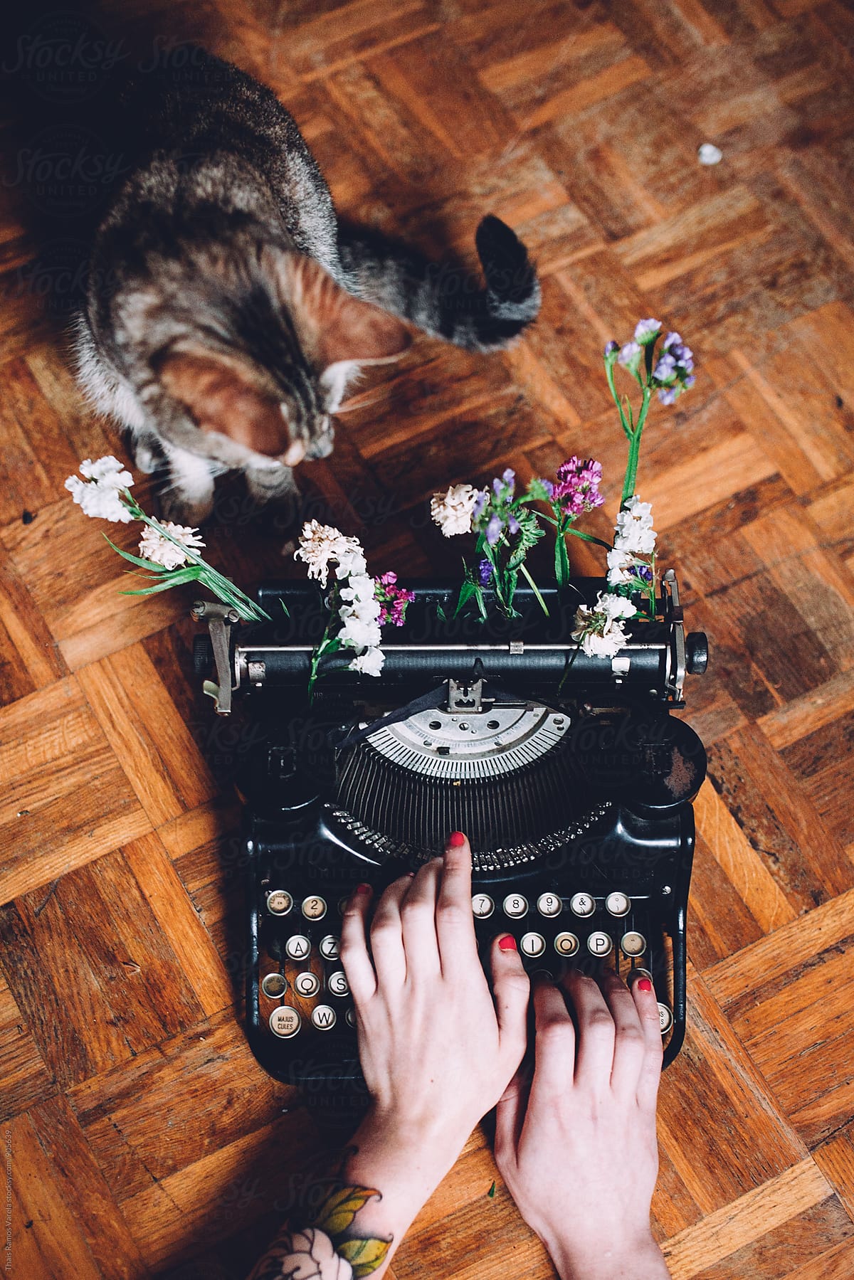 woman typing with a vintage typewriter with flowers and cat