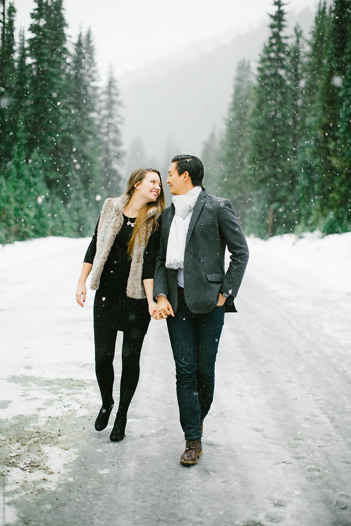 Young engaged couple holding each other in the winter snow.