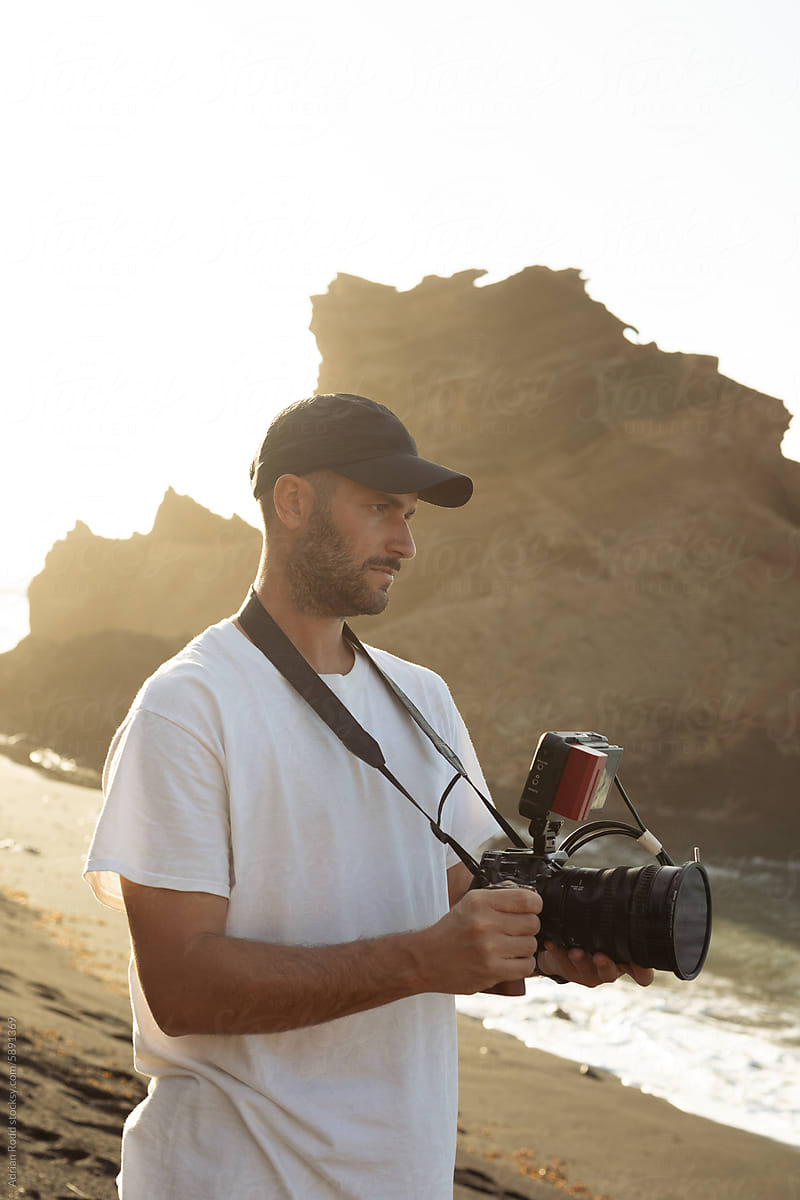 Videographer is using a video camera to capture a serene coast