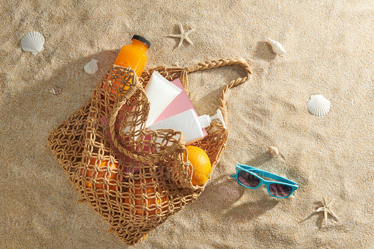 Beach accessories on the sand. Bag, sunglasses and orange juice