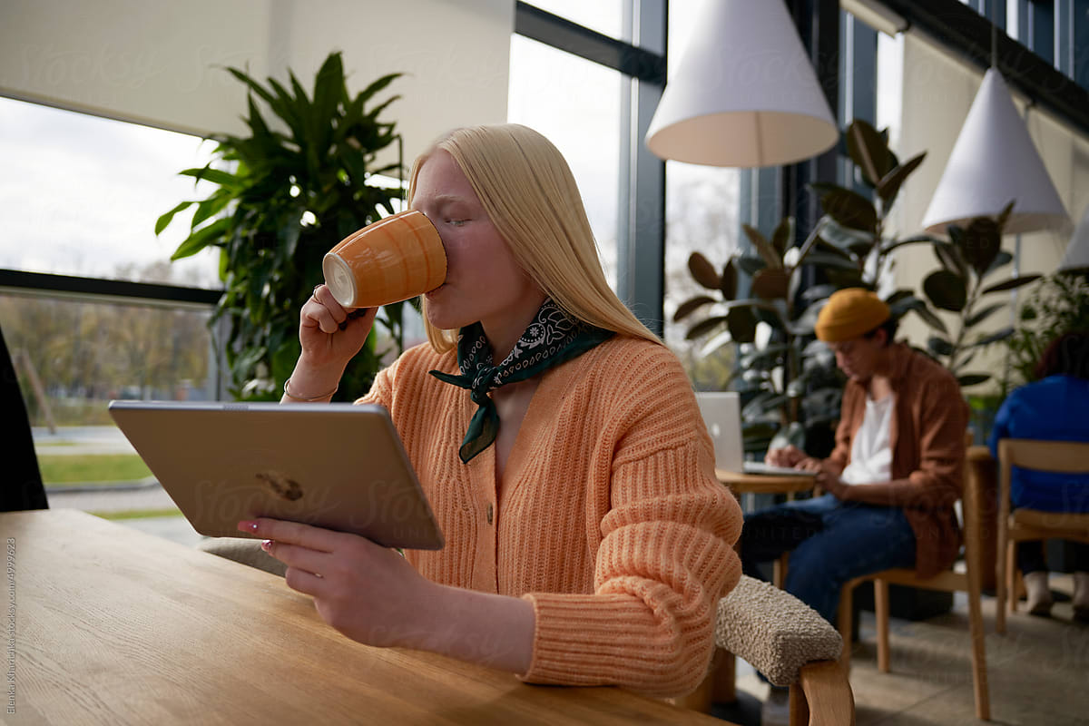 Woman drinking hot beverage using tablet