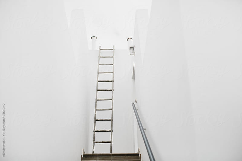 ladder at the end of stairway in white wall home