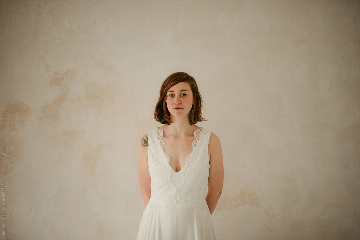 Emotionless contemporary bride with tattoos in wedding dress