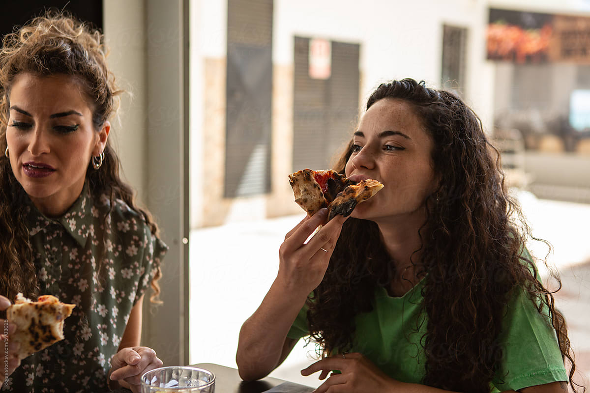 Woman bites a pizza slice