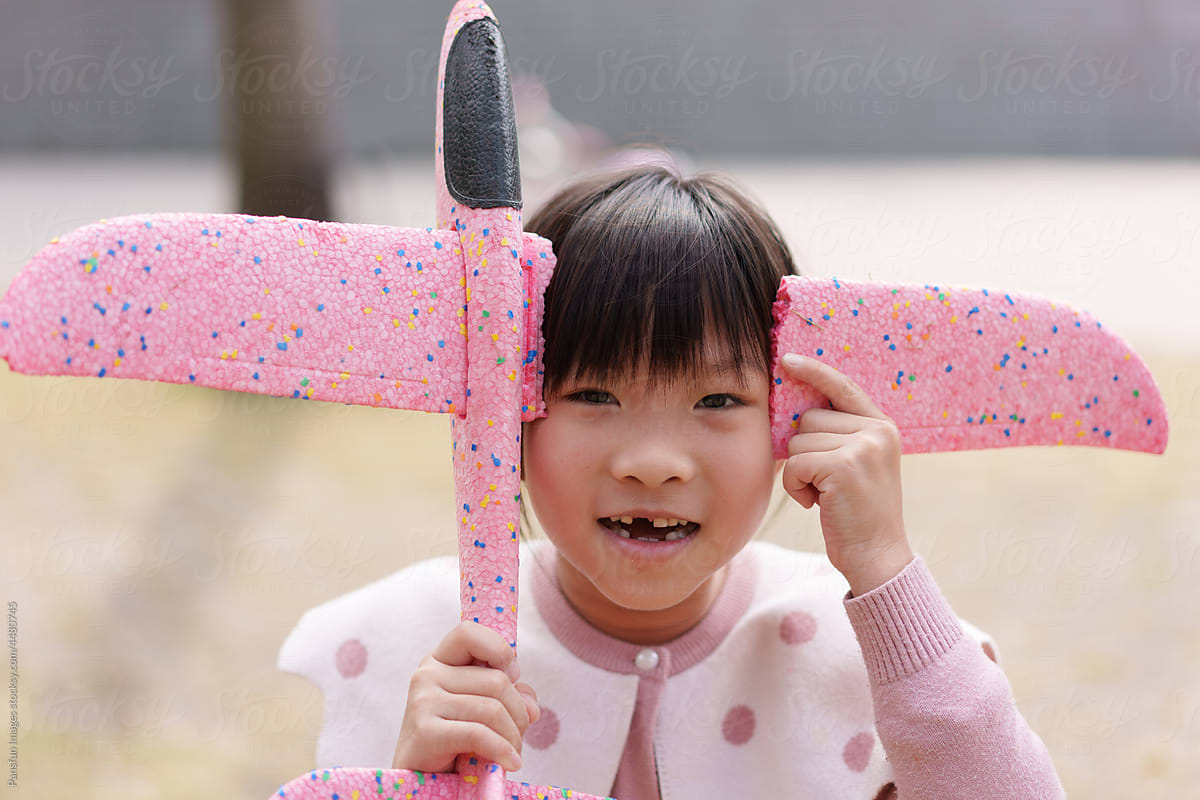 little girl holds a broken toy airplane