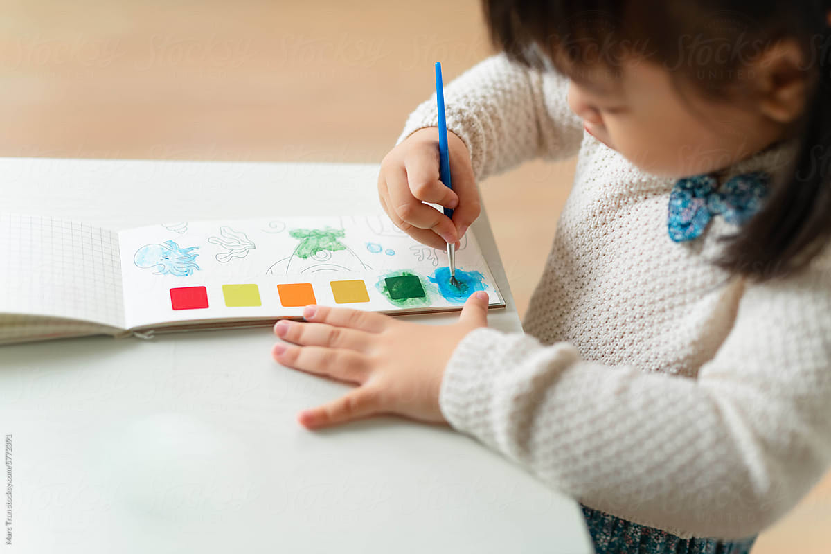 Cute cheerful child play with paints in preschool