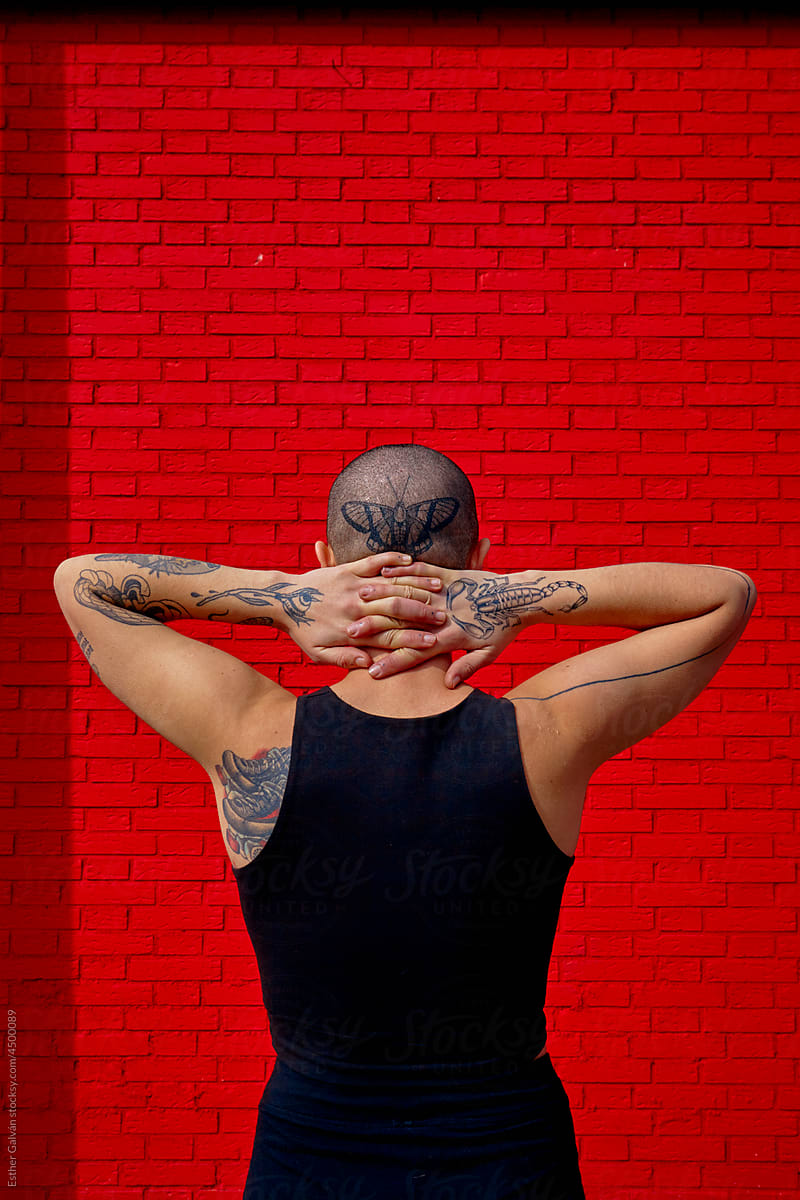 Back of a queer model with tattoos and shaved hair vertical