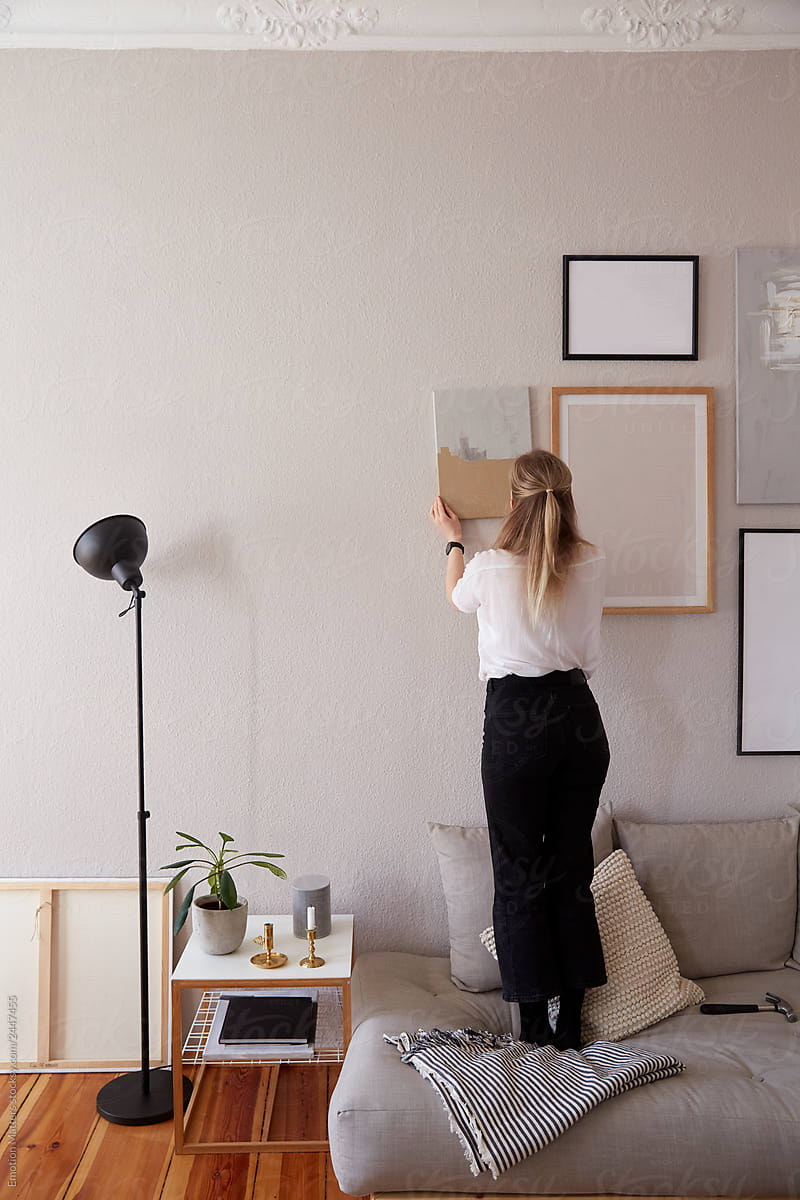 A woman hang a painting ( Wall art belong to owner)
