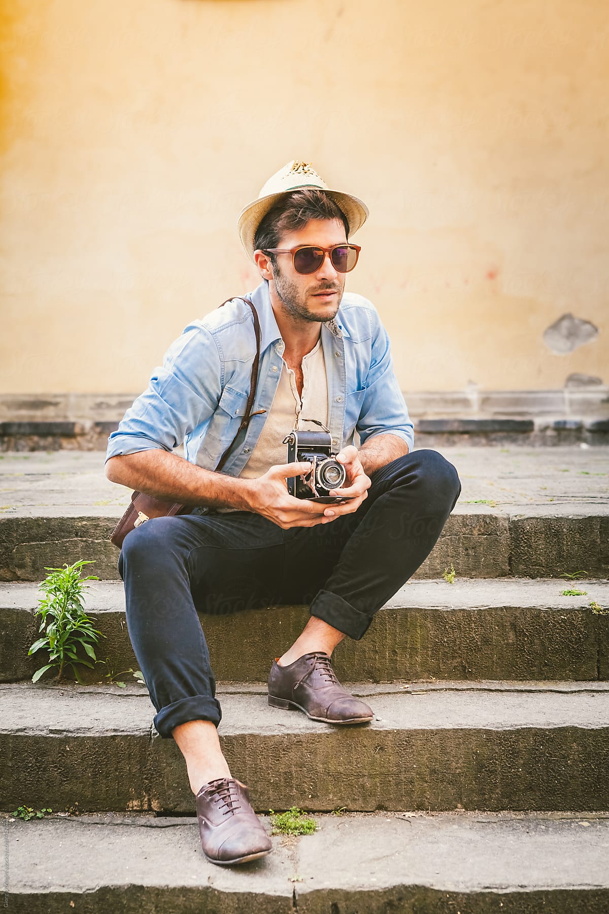 Hipster Man with Retro Camera Sitting on a Staircase