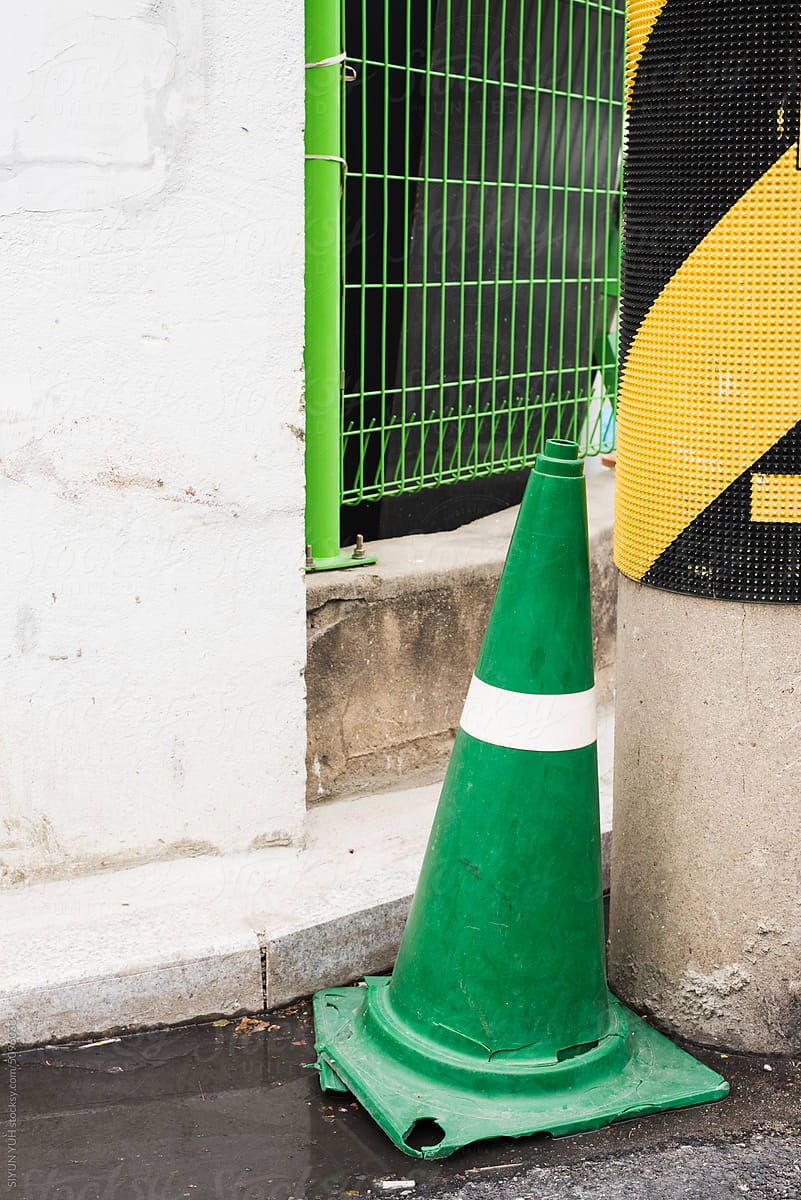 Green traffic cone in colorful city