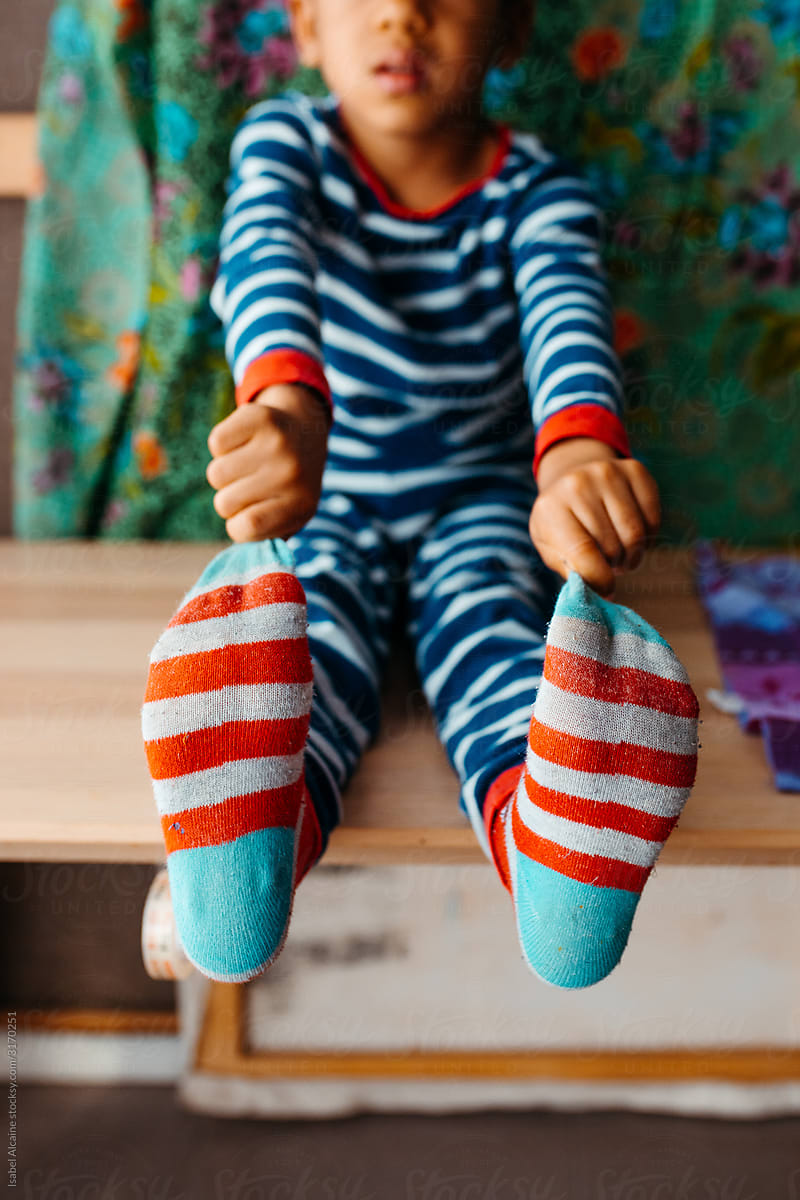 Mixed race boy in striped pajamas grabbing his striped socks.