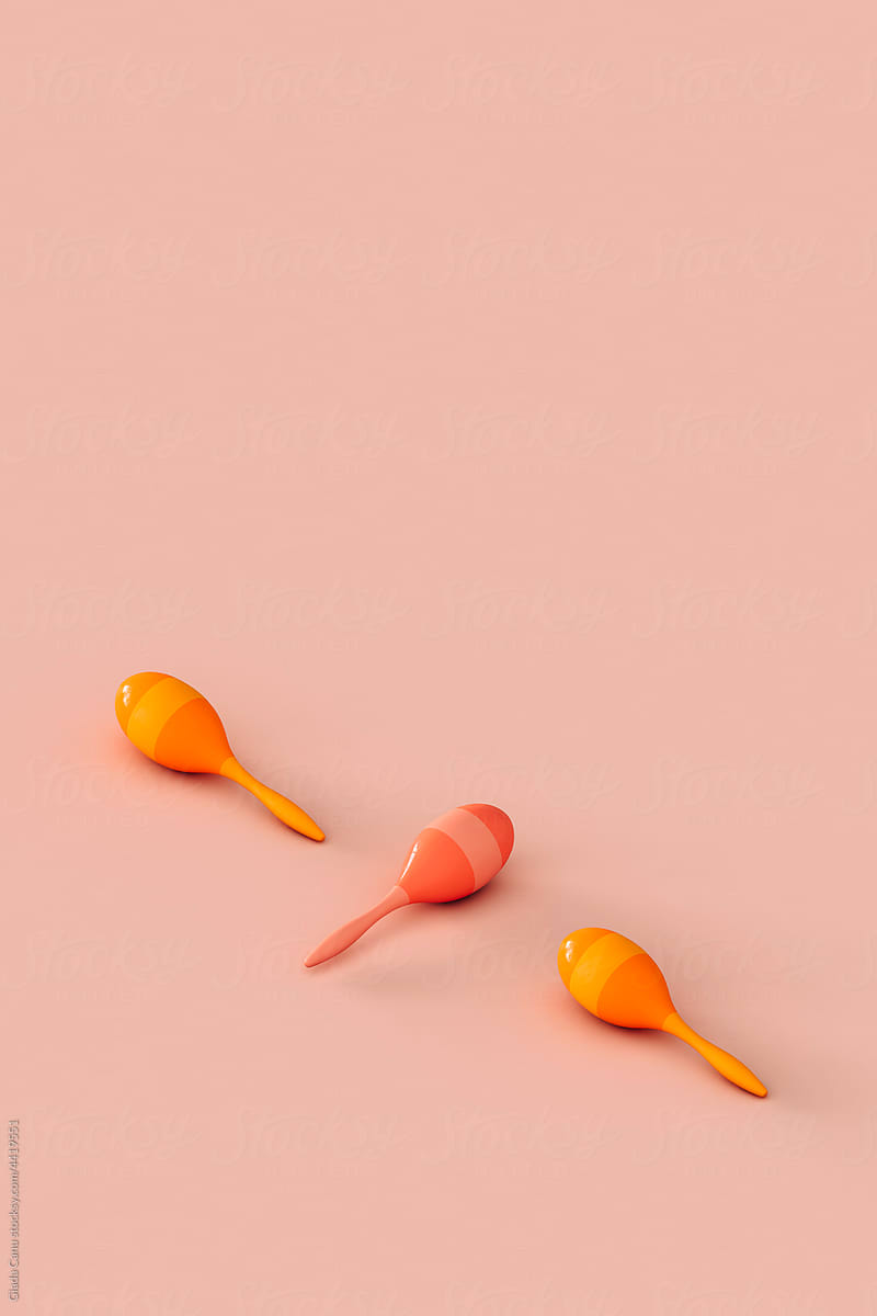 three colorful maracas on a pink background