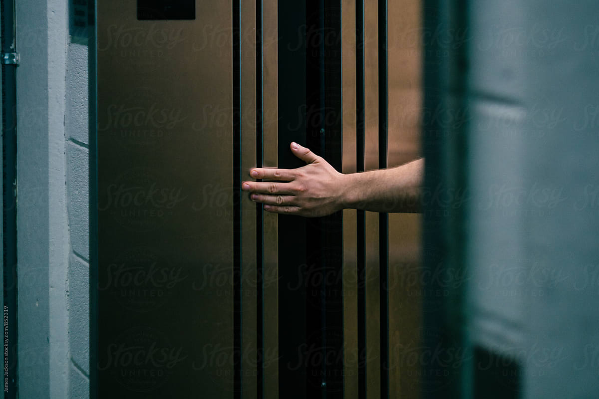 A caucasian man\'s hand holding open elevator doors