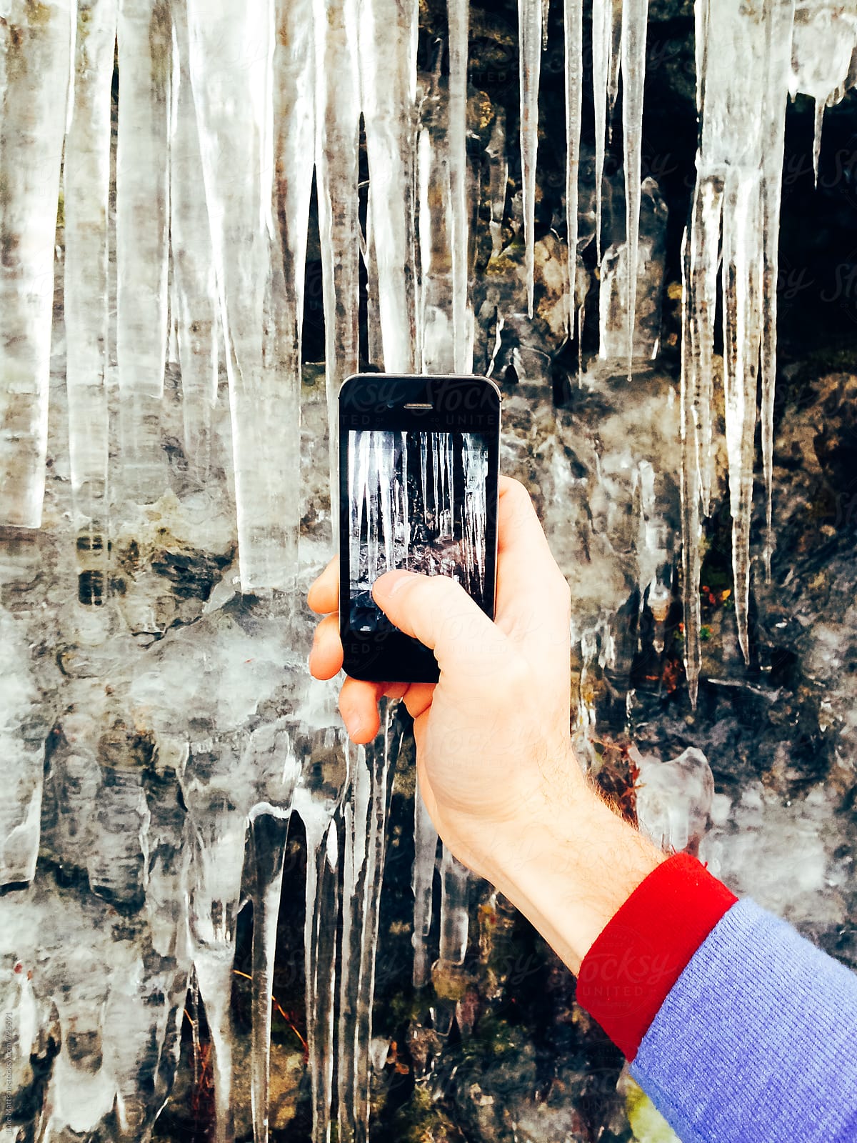 Man Holds Hand Out To Take Picture Of Icicles Using Smart Phone