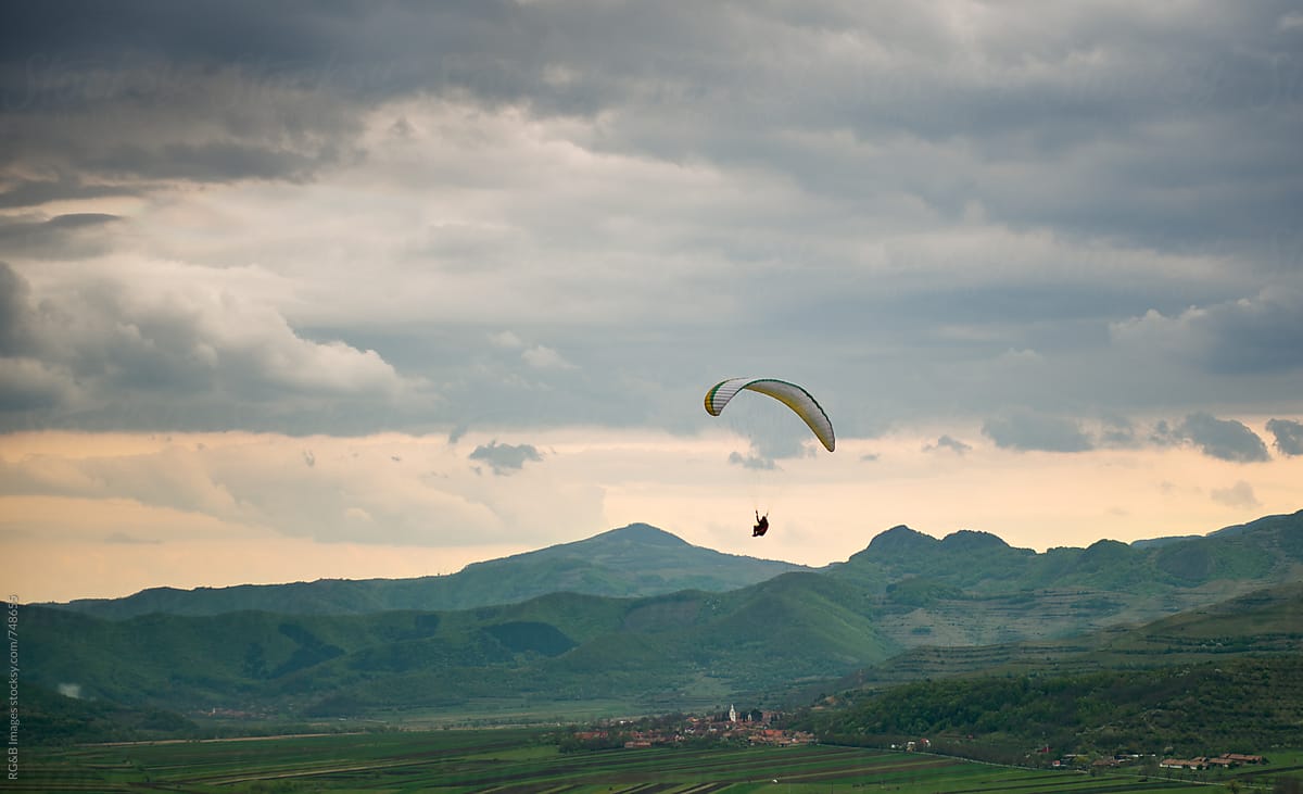 Paraglider flying over a small village