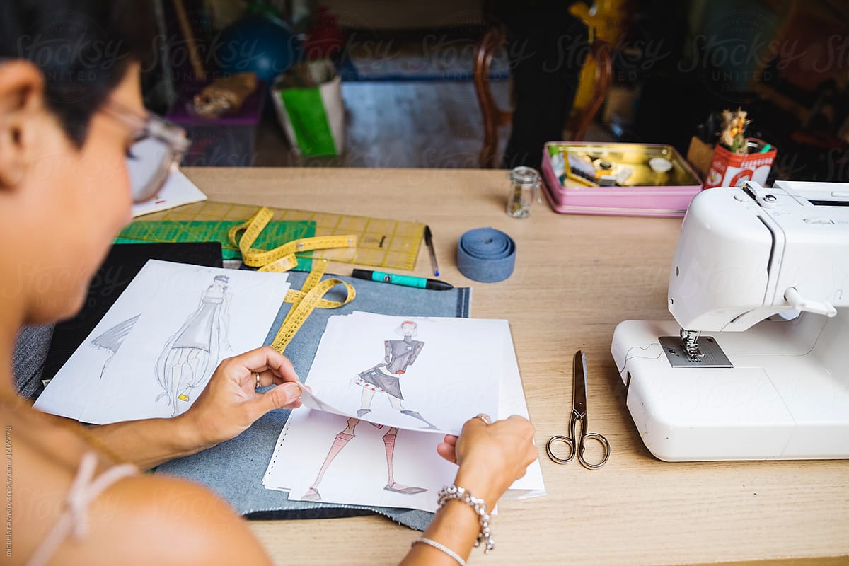 Fashion designer look at her sketches of clothes in her atelier