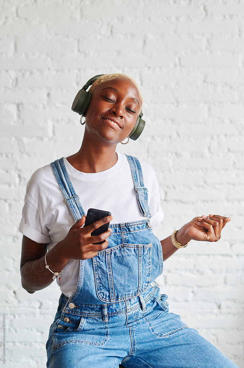 Young Woman Listening To Music On Headphones By Stocksy Contributor