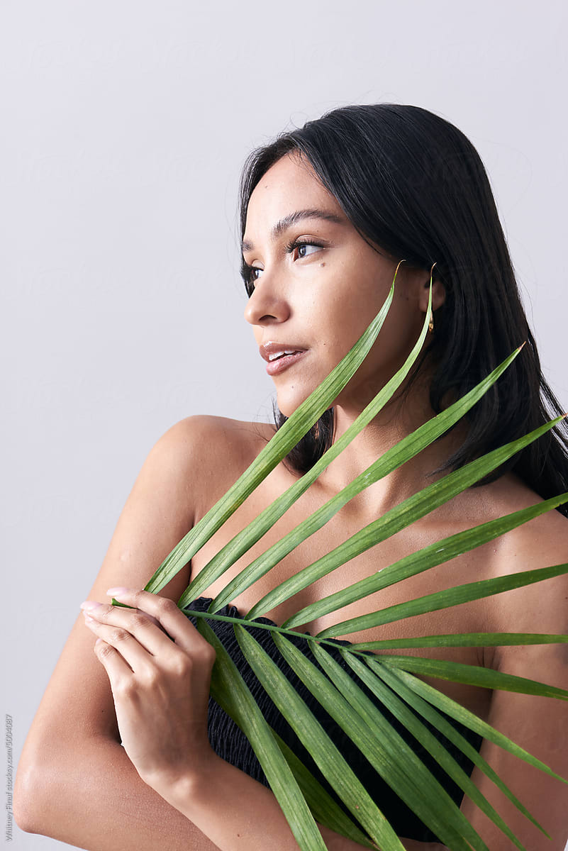 Latina Woman Holding Majesty Palm Leaf to Her Face