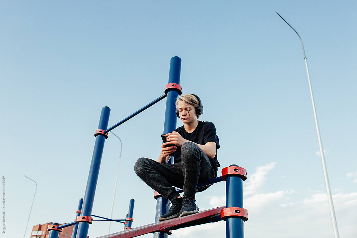 Teenager listening to music on sports ground