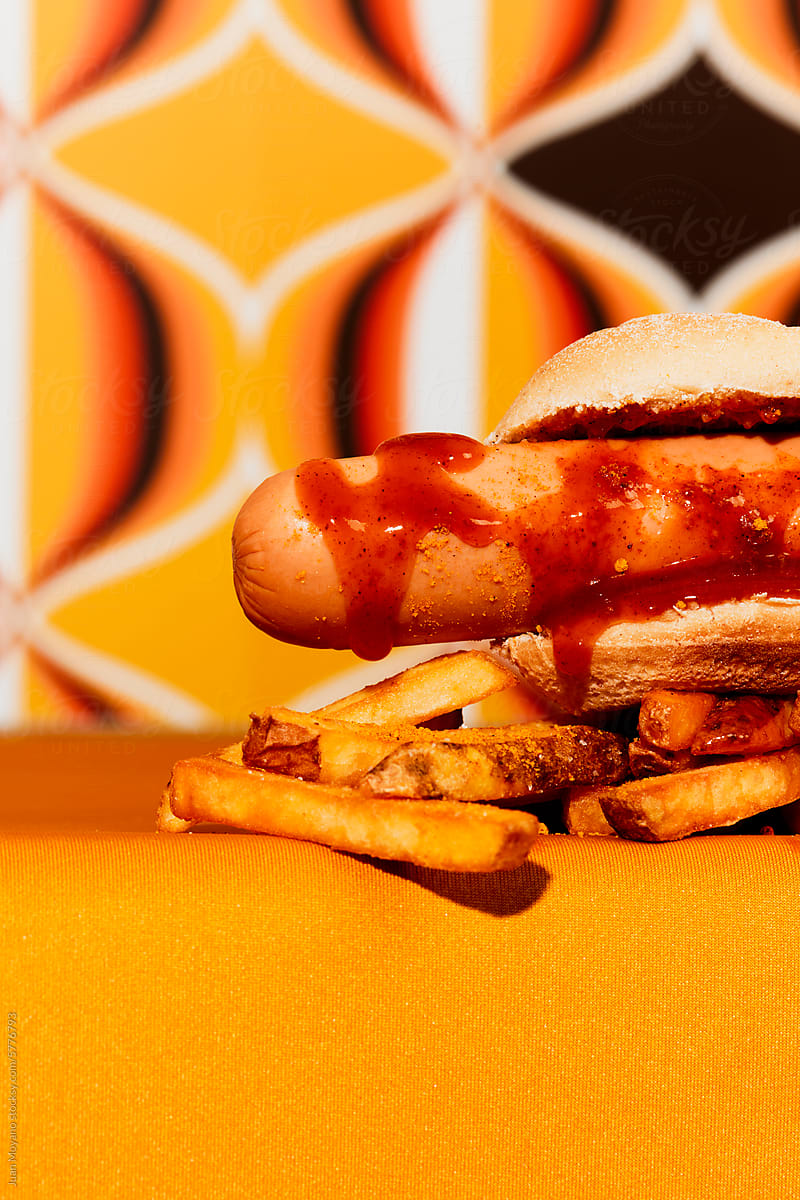 currywurst served in a bread bun and french fries