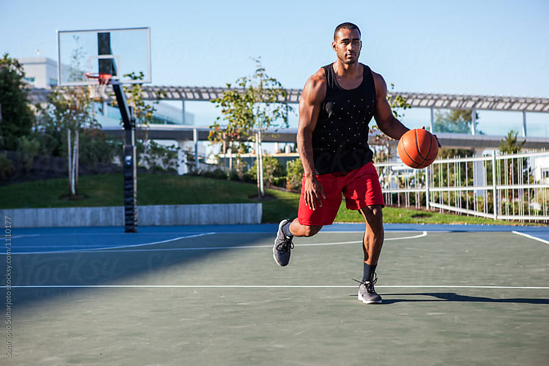 African American man dribbling a basketball on an outdoor court
