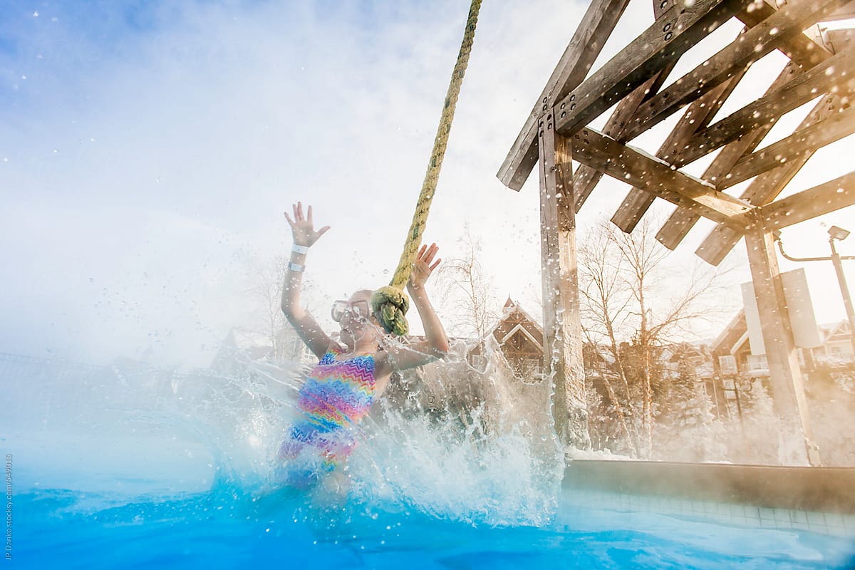 Girl Jumping Into Outdoor Pool at Ski Lodge in Winter
