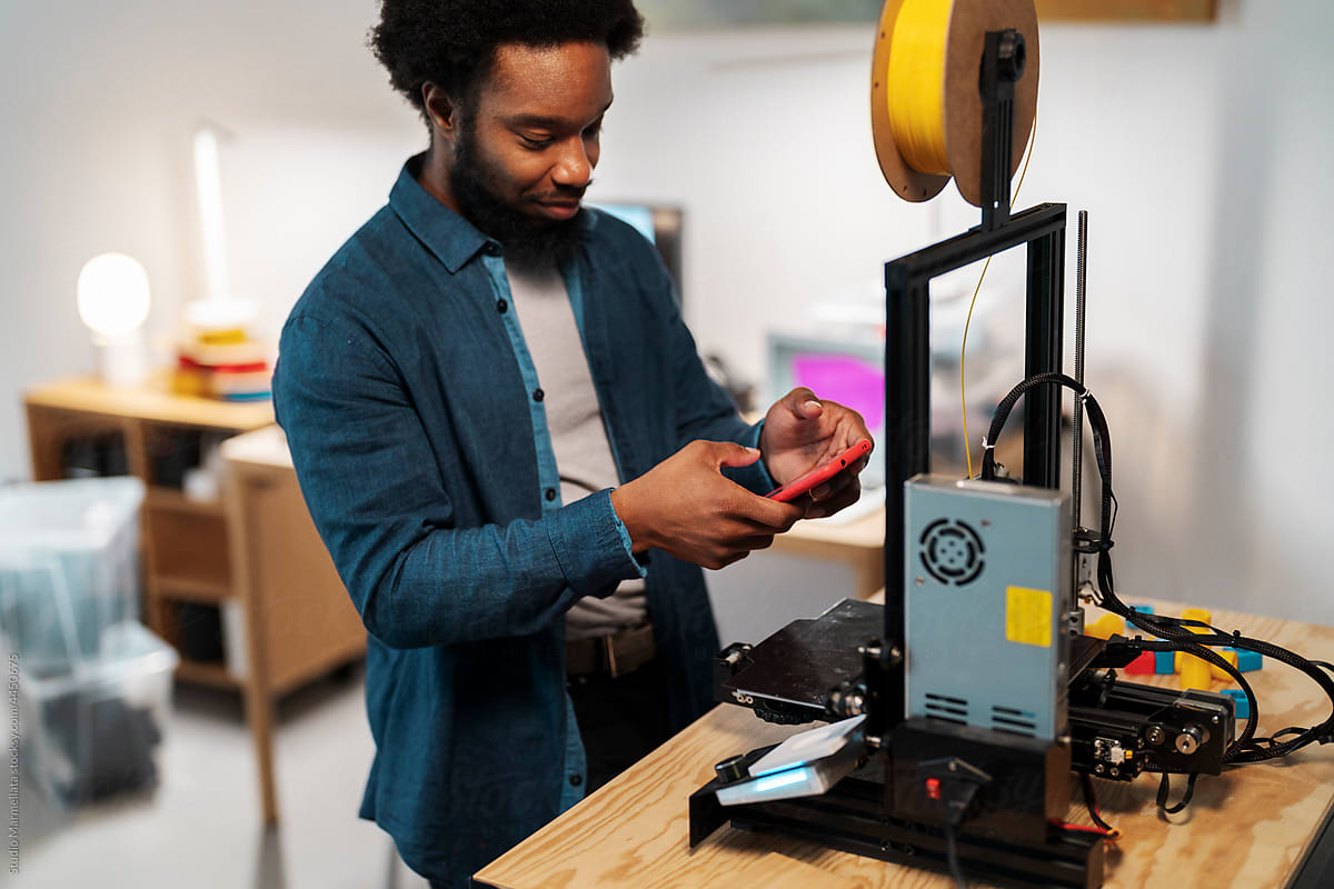 Male 3D designer working on printer in workroom