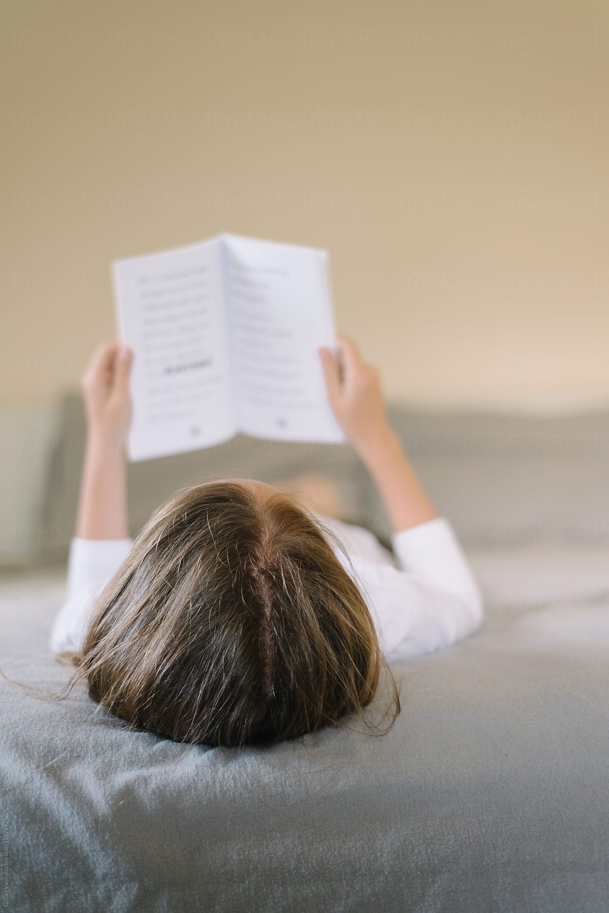girl reading a book lying on a bed