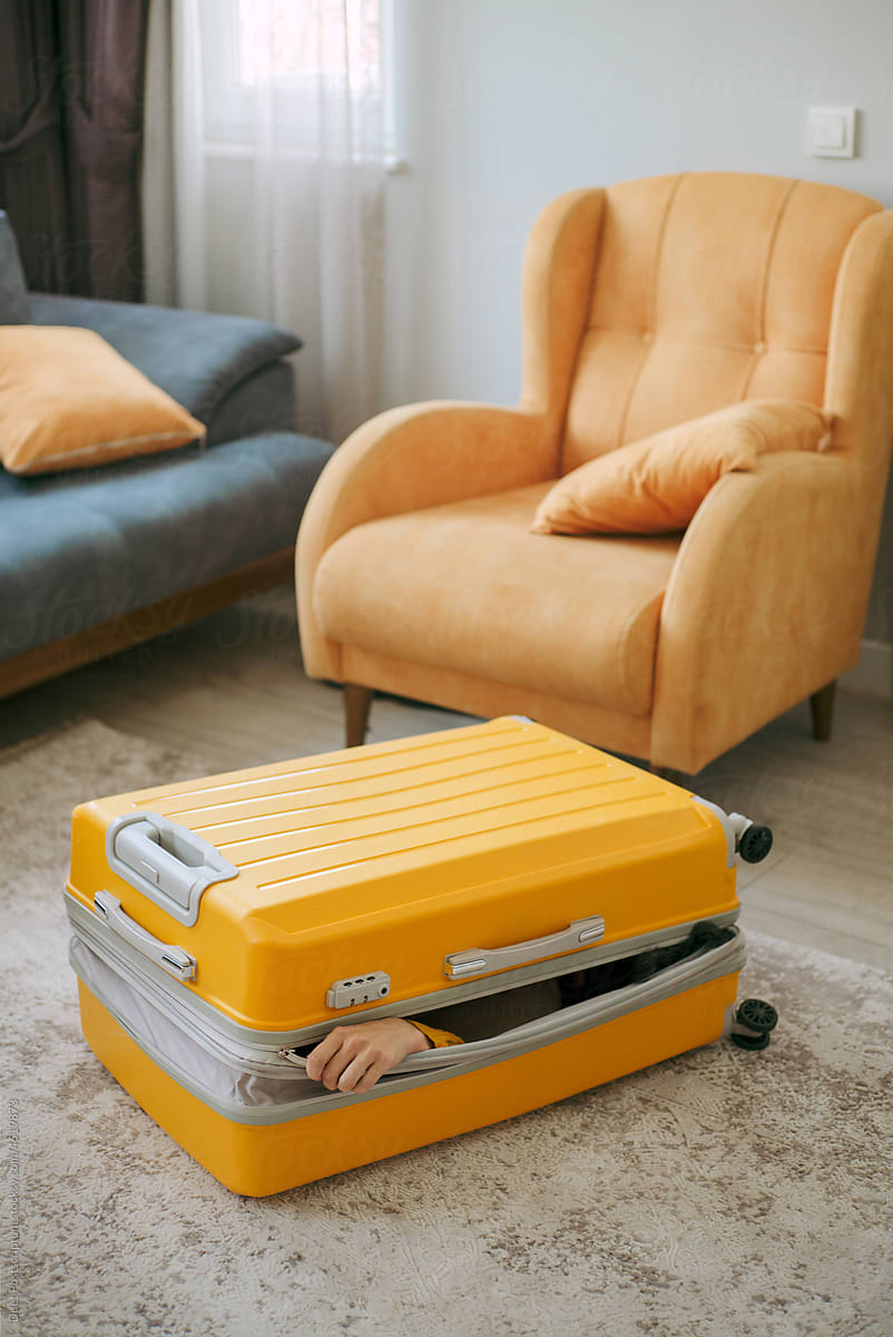 An unrecognizable person packed into a travel suitcase