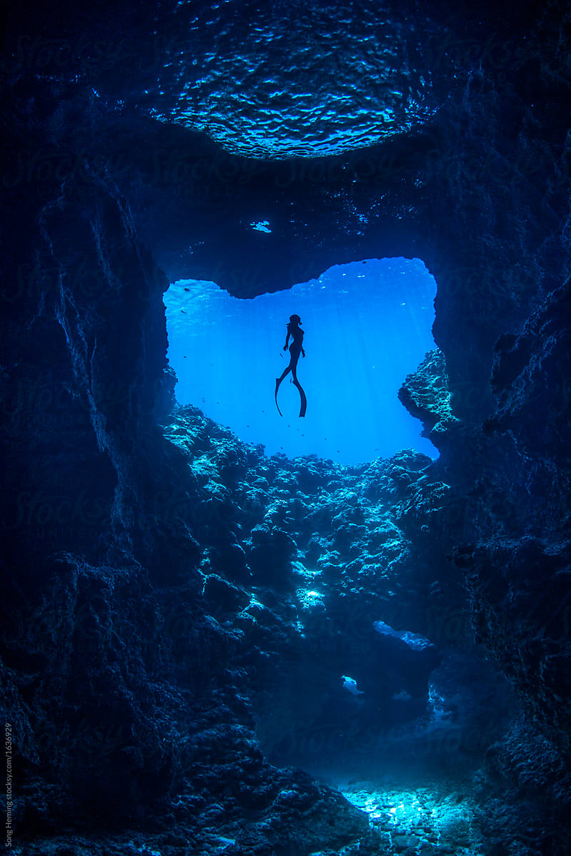 A female free diver diving in the cavern