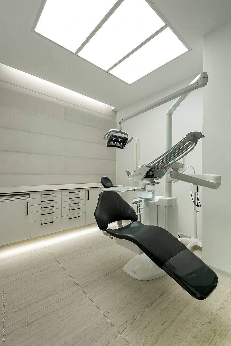 Interior of modern dental practice room with chair, lamp and equipment