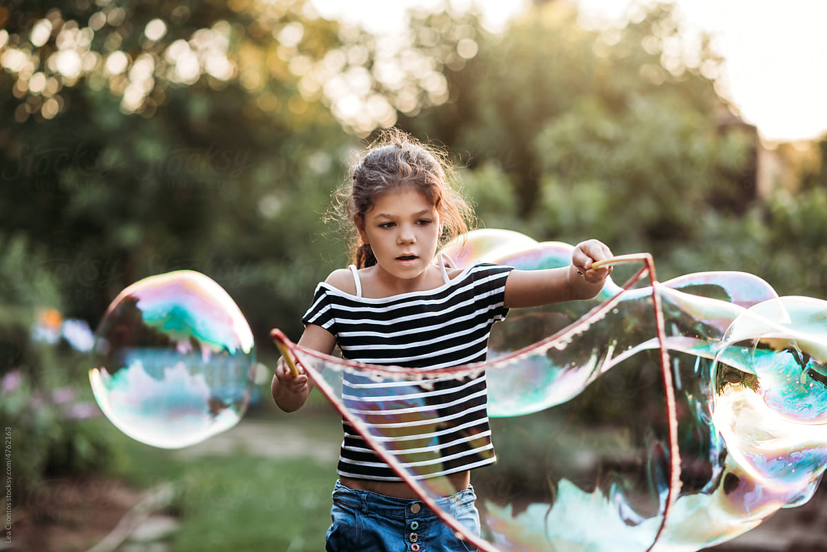 Young girl is creating giant soap bubbles.
