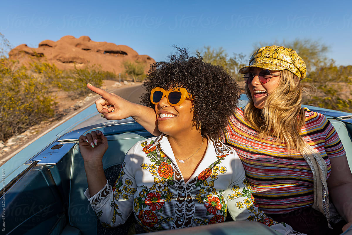 Happy Friends riding in the back of Convertible Looking at sites