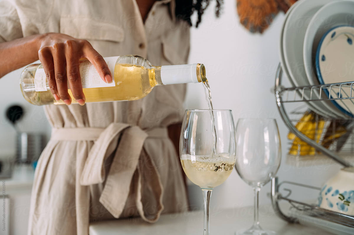 Woman pouring wine into glasses at home