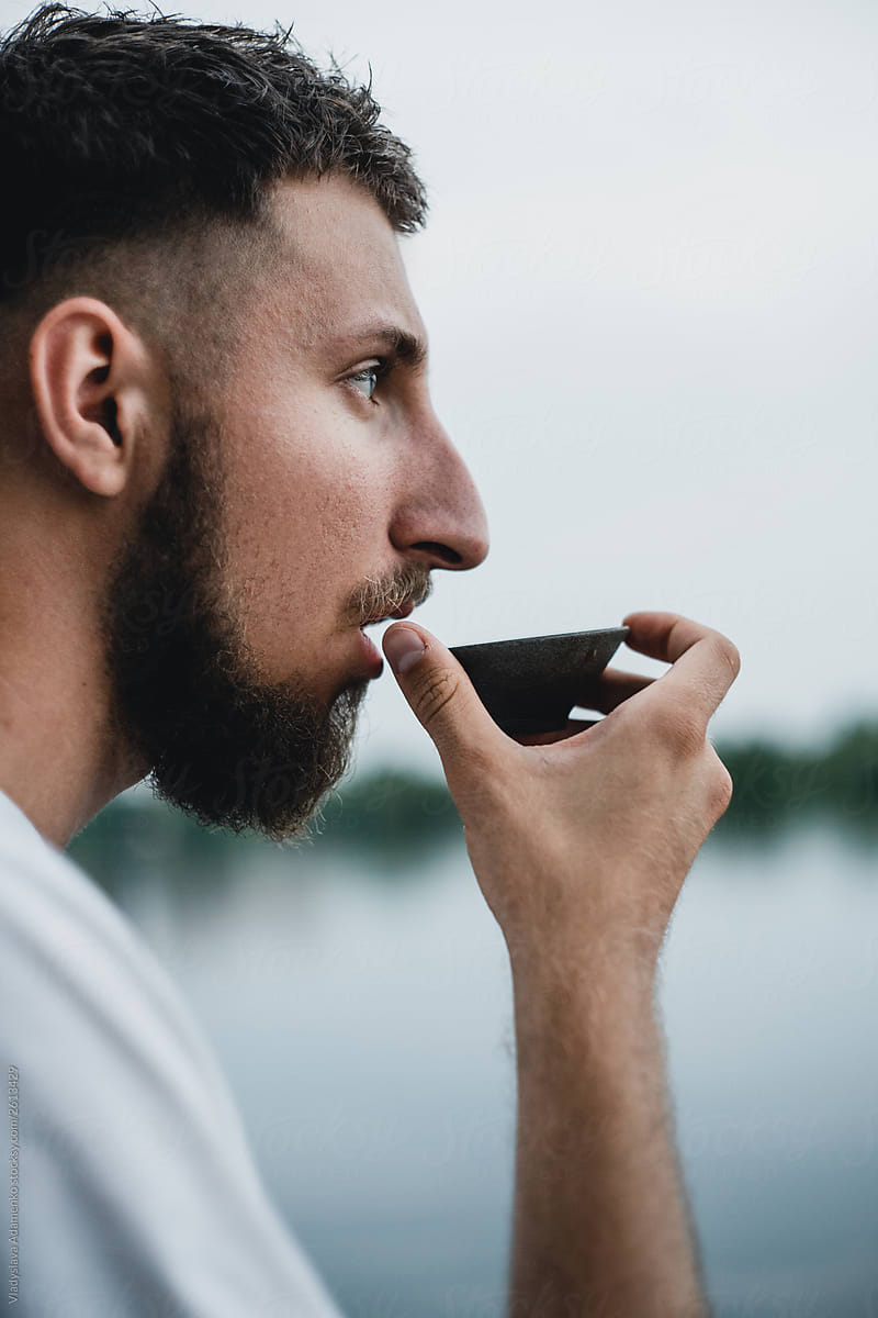 Young man drinking tea with eyes open outdoor